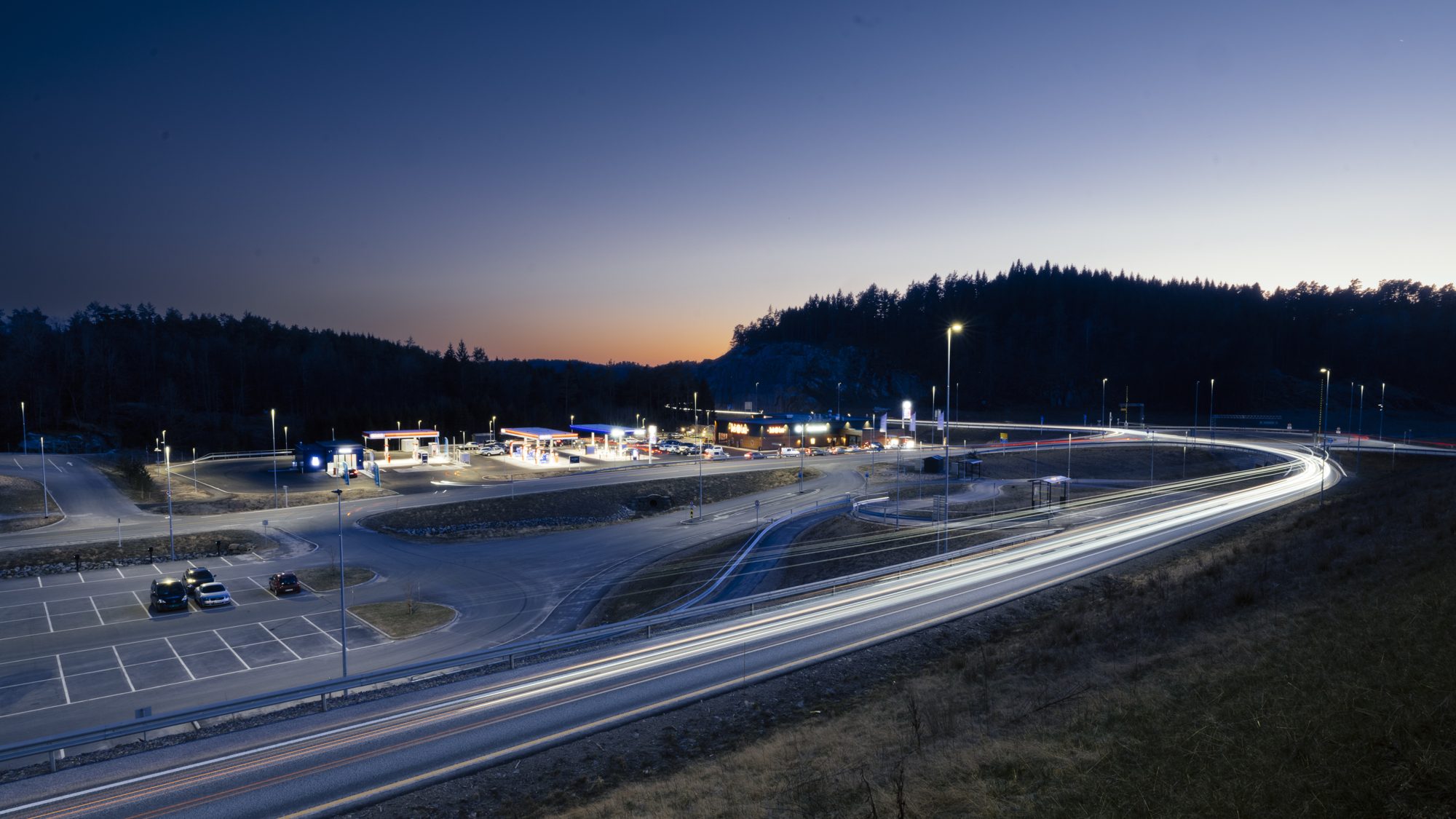 Roadside retail forecourt at dusk with light trails